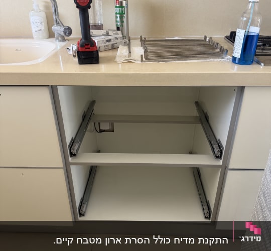 ארון מטבח פתוח עם כלים וחומרי ניקוי